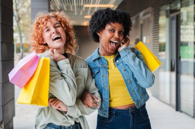 İki neşeli arkadaş alışveriş yaparken, canlı çantalar tutarken ve heyecandan kahkahalar atarken, keyifli gezilerinde eğlencenin ve arkadaşlığın özünü yakalarken, keyifli bir anı paylaşıyorlar..