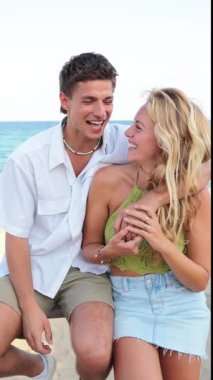 Neşeli bir çift kumsalda eğleniyor. Güneşin altında birlikte el sallayıp gülüyorlar. Bu romantik an, mükemmel bir yaz gününde aşkın ve sevincin özünü yakalar..