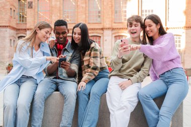 Bir grup hevesli genç, akıllı telefonlarıyla etkileşim kurarak, çeşitli uygulamaları keşfederek ve heyecan verici keşifleri canlı bir şekilde paylaşarak eğleniyorlar.