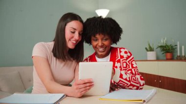 Mutlu ve hevesli genç kadınlar bir tablet üzerinde heyecan verici bir şey keşfederken ortak bir çalışma sırasında arkadaşlıklarını ve bağlantılarını sergileyerek keyifli bir an yaşıyorlar.