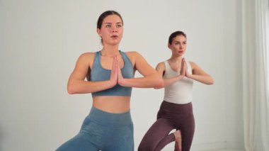 Kendini yogaya adamış iki kadın birlikte çalışırken dengelerini, güçlerini ve konsantrasyonlarını sergilerler. Bu görüntü zindeliğin, sağlığın ve uyumlu hareketin özünü yakalar.