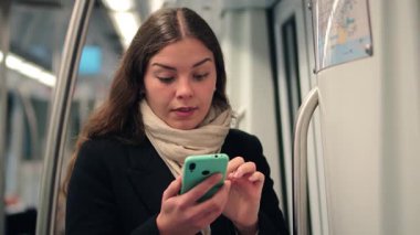 Yol tarifi bulmak için telefon kullanırken dikkatli bir şekilde kadın yolcuya odaklanmak, metro sisteminde güven ve netlikle gezinmede kararlılık ve bağlılık göstermektedir.