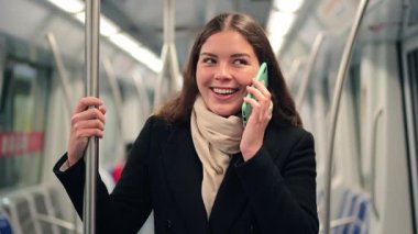 Neşeli bayan yolcu, metroda seyahat ederken akıllı telefonuyla canlı bir sohbete daldı. Ulaşım sırasında günlük hayatındaki iletişim ve bağlantının rahatlığını gösterdi.