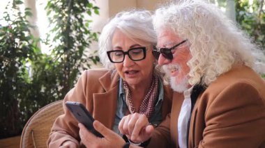 Yaşlı çift mutlu bir şekilde akıllı telefonlarını kullanarak mutlu anları paylaşıyor, hayatlarındaki aşk ve teknolojinin güzelliğini resmediyor ve birlikte geçirdikleri deneyimin tadını çıkarıyorlar. Yüksek