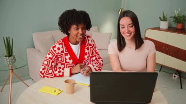 İki hevesli genç kadın verimli bir çalışma oturumuna katılıyor, fikirleri paylaşıyor ve çalışma alanında notlar yazıyor, arkadaşlarımız arasındaki işbirliği ve desteğin önemini vurguluyor.