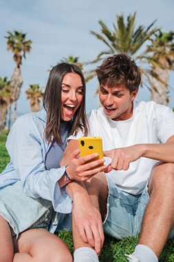 Neşeli bir çift, akıllı telefonlarındaki bir uygulamayı keşfederken keyifli deneyimleri paylaşırken aynı zamanda neşe ve bağlantı ifade ediyorlar..