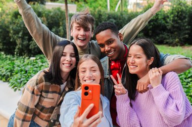 Neşeli bir grup çok ırklı arkadaş, akılda kalıcı bir selfie 'yi akıllı bir telefonla yakalıyor, neşeli ifadelerini sergiliyor ve gençliğin ve arkadaşlığın bu iç açıcı ve canlı anında yakın bağlarını kuruyorlar..