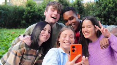 Bir grup genç, arkadaşça bir toplantıda selfie çektirirken eğleniyor. Beş karışık arkadaş gülümsüyor ve gülüyor. Öğrenciler birlikte kameraya bakıyor. Erkekler ve kadınlar eğleniyor