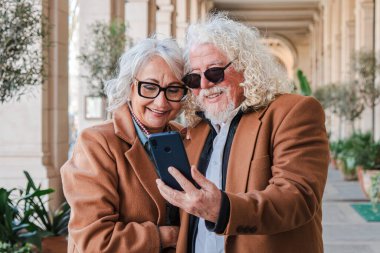 Mutlu son sınıf çifti, akıllı telefonlarına bakıp gülüşlerini ve gülüşlerini paylaşırken birlikte anılarını yakalıyorlar, hayatlarındaki bağ ve aşkın güzelliğini gösteriyorlar.