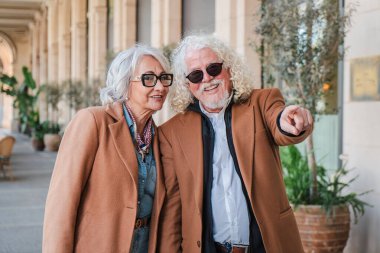 Neşeli son sınıf çifti dışarıda güzel bir anı paylaşıyor. Büyüleyici bir şeye hevesle işaret ediyorlar. Birlikte vakit geçiriyorlar.