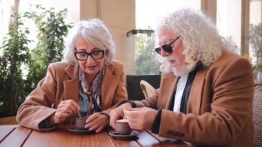 Çekici, yaşlı bir çift içten bir sohbete dalıp, kahve ve tatlı ikramlardan keyif alıyorlar, kahkaha ve neşeyi paylaşıyorlar, keyifli etkileşimleriyle değerli anılar yaratıyorlar.