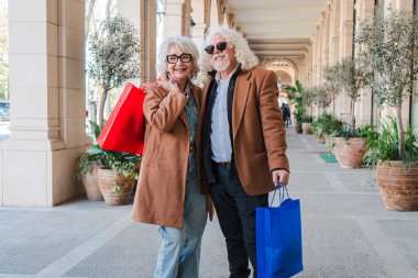 Yaşlı çift eğlenceli bir alışverişe çıkar, neşeli bir alışveriş torbası taşır, kahkahalarını ve gülümsemelerini paylaşır, keyifli günlerinde güzel anılar yaratırlar.