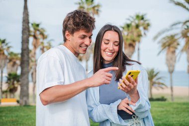 Mutlu çift, açık havada akıllı telefon uygulamasına göz atarken canlı bir etkileşime girmiş.