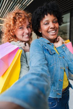 Heyecanlı arkadaşlar keyifli bir alışveriş deneyimini paylaşıyorlar. Parlak alışveriş torbalarıyla unutulmaz bir selfie çekiyorlar. Eğlenceli bir günde mutluluklarını ve bağlantılarını sergiliyorlar..