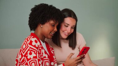 Two cheerful ladies capturing a joyful moment together as they embrace and celebrate their friendship while taking a selfie with a smartphone, radiating happiness and excitement in a lively atmosphere