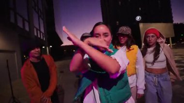 Canlı bir arkadaş grubu coşkuyla dans ediyor, müzik ve harekete olan sevgilerini sergiliyorlar yaratıcılığın ve yoldaşlığın canlı ve enerjik bir göstergesi olarak..