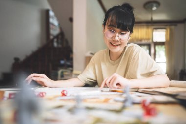 Masa üstü ve masa başı oyunu hobisi. Genç Asyalı kadın hikaye anlatmaktan zevk alıyor. Canavar minyatürleri ve zar bileşenleriyle bulanık arkaplan.