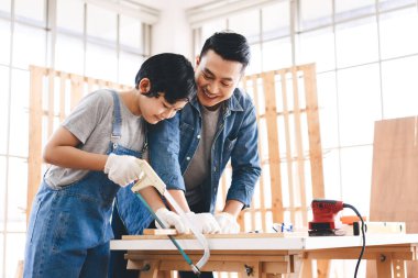 Southeast asian family father and son diy or repair at home concept. Dad teach using tools about carpenter or engineer education skill with child at workshop.