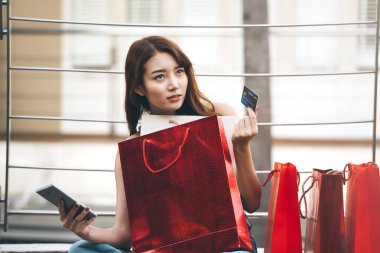 Tatillerde bekâr olmak. Kredi kartı ve alışveriş torbaları tutan genç Asyalı kadın. Nakitsiz konsept ile satın alma.