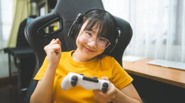 İnek stili genç Asyalı oyuncu kadın gözlük takıyor ve online oyun oynuyor. Zafer havası için rekabet. İnsanlar evlerinde boş zaman geçiriyorlar..