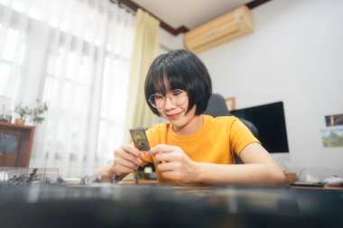 Ev kavramında ilginç hobileri olan insanlar. Masanın üzerinde oyun oynayan Asyalı genç bir kadın. Gülümseyerek ve kameraya bakarak mutlu..