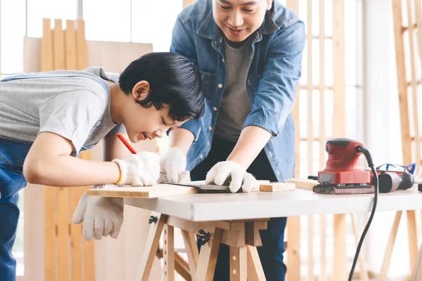 Southeast asian family father and son diy or repair at home concept. Dad teach using tools about carpenter or engineer education skill with child at workshop.