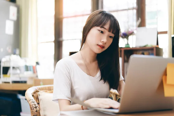 College student study online stay at home for social distancing and new normal concept. Cute asian teenager woman using laptop for internet education. Background cozy style room workplace.