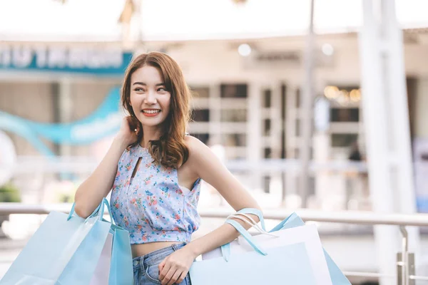 休日の独身生活をしている ショッピングバッグで育った幸せな若い大人のアジアの女性の手 コピースペースの背景 — ストック写真