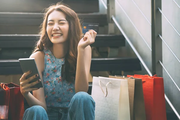 People spending money for trend fashion concept. Happy young adult southeast asian woman with shopping bags on day. Wear blue shirt with long hair.
