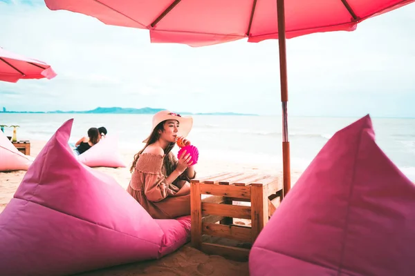 Adult single asian beauty woman relax at the beach concept. At trendy chic pink cafe drinking refreshment. Happy summer single vacation lifestyle. Background with copy space. Pattaya, Thailand.