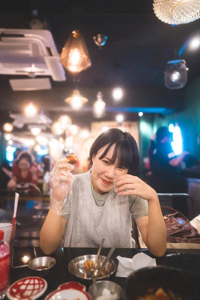 Dinner couple date at indoor restaurant concept. Portrait happy smile young adult asian woman cheer with soju at Korean chicken meal. Foodie people lifestyle.