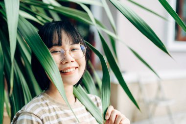 Young adult asian woman satisfaction lifestyle at home. People hobby gardening in green environment backyard at outdoor day. Wellness happy face wear eyeglasses.