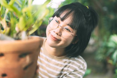 Portrait of young adult asian woman lifestyle at home. Leisure people walking in garden at backyard on day. Wellness happy face wear eyeglasses.
