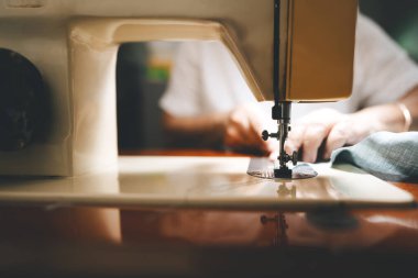 Closed up sewing machine and blur background with retriement tailor no face crafting a cloth. Baby boomer generation mature working at home concept.