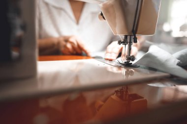 Closed up sewing machine and blur background with retriement tailor no face crafting a cloth. Baby boomer generation mature working at home concept.