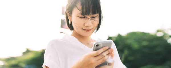 年轻的亚洲女商人使用手机应用程序 单一女性类型的讯息通过互联网在线 城市生活方式工作的人 在室外阳光下 — 图库照片
