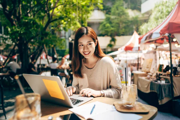 Business freelancer young adult asian woman using laptop computer for work at sidewalk cafe. Happy and smile face. Urban people lifestyle with modern technology via internet online on day.
