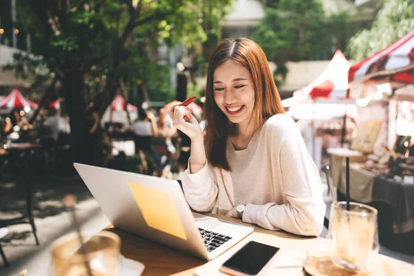 Business freelancer adult asian woman using laptop computer for work at sidewalk cafe. Happy and smile face. Urban people lifestyle with modern technology on day.