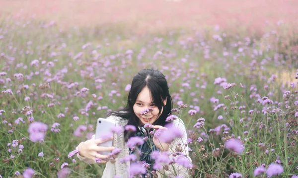 自然の概念でアウトドア旅行 春や夏の朝の気分で野生の花公園フィールドで携帯電話を使用して若い大人のアジアの女性と山の谷の上 — ストック写真