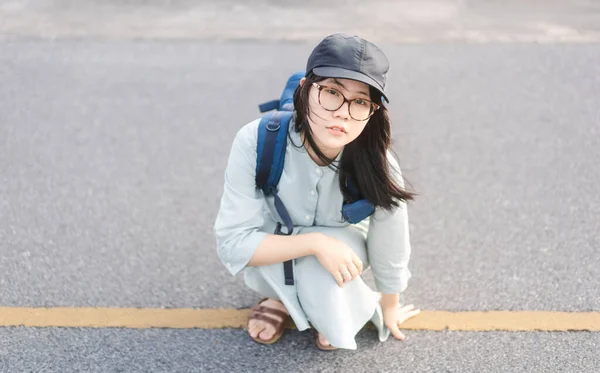 青いバックパックを持つ肖像若い大人のアジアの旅行者の女性 路上で座っている 目をカメラを見て 夏休みの一人旅のコンセプト — ストック写真