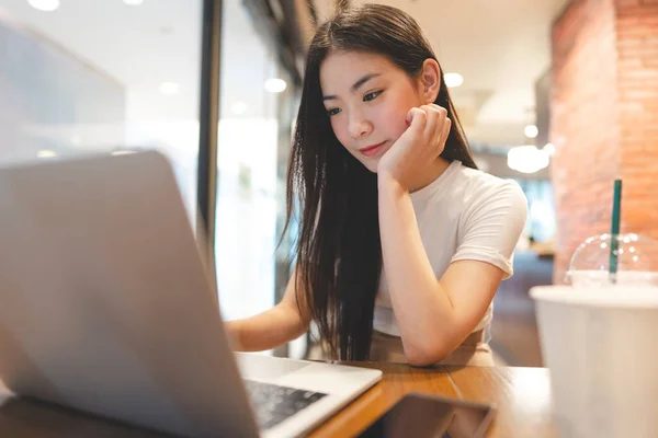 在咖啡店使用笔记本电脑工作的亚洲年轻女性自由职业 城市人的生活方式与现代技术日新月异 数字游牧民 — 图库照片