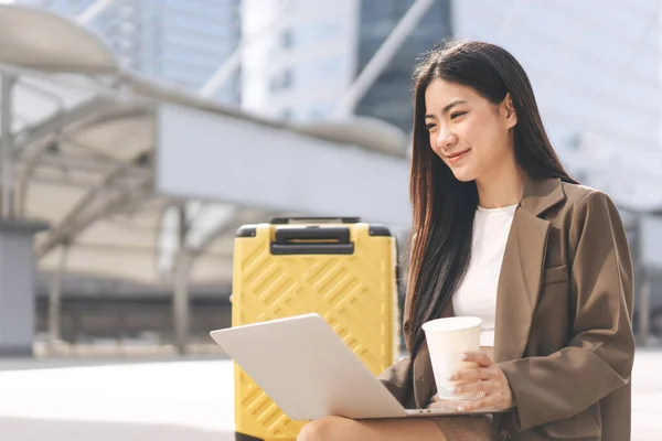 商业自由职业的亚洲成年女性使用笔记本电脑 美丽的微笑面对长发 每天都带着旅行箱坐在户外 城市居民的生活方式 — 图库照片