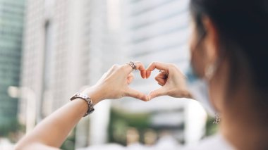 Bekar bir kadının kalp hareketiyle el ele tutuşması. Sevgililer gününde sevgililer günü için gümüş aksesuarı ve cazibe kullan. Şehir halkı yaşam tarzı konsepti.