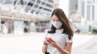 Genç yetişkin iş kadını, Corona virüsünü veya Covid19 'u ve hava kirliliğini korumak için yüz maskesi takıyor. Gündüz konseptinde halk sağlığı olan şehir halkı yaşam tarzı. Kameraya bakan kadın portresi.