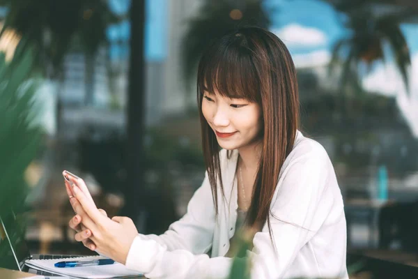 大学生教育生活方式 工作和学习日时间观念 利用手机在室内咖啡店网上申请的亚裔年轻女生 — 图库照片