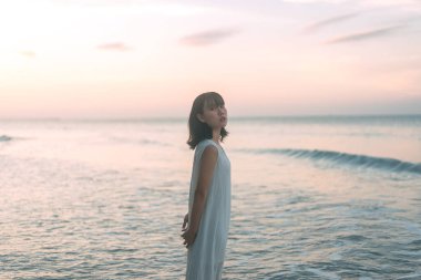 Sahildeki Asyalı kadın portresi. Deniz dalgalarında yürüyorum. Güneş ışığı arka planında. Açık hava yaşam tarzı gündüz konsepti.