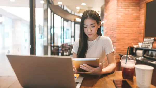 在咖啡店工作的亚洲年轻女性自由职业人士使用平板电脑 城市人的生活方式与现代技术日新月异 数字游牧民族 笑容满面 — 图库照片