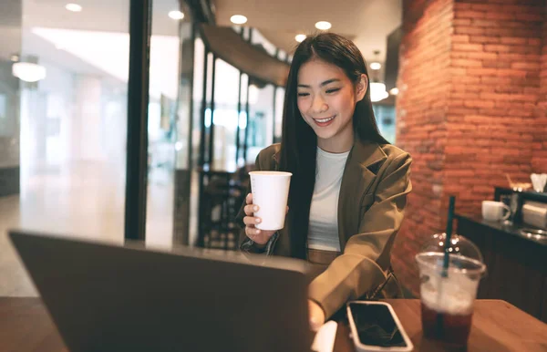 亚洲年轻的自由职业女性在咖啡店里拿着咖啡杯 都市人的生活方式使工作时间中断 笑容满面 — 图库照片