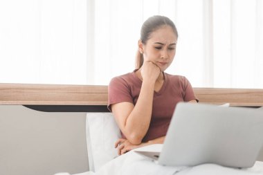 İnternet teknolojisi konseptiyle yaşam tarzı rutini. Ağlayan yetişkin Asyalı kadın teletıp zihinsel sağlığı için online terapi yatağında dizüstü bilgisayar kullanıyor..