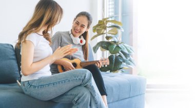 İlişki konseptiyle birlikte yaşayan iki yetişkin kadın. Güneydoğu Asyalı çiftler evlerinde kanepe hayatı anlarında müzik dinleyerek rahatlar. Sancak boyutu arkaplan.